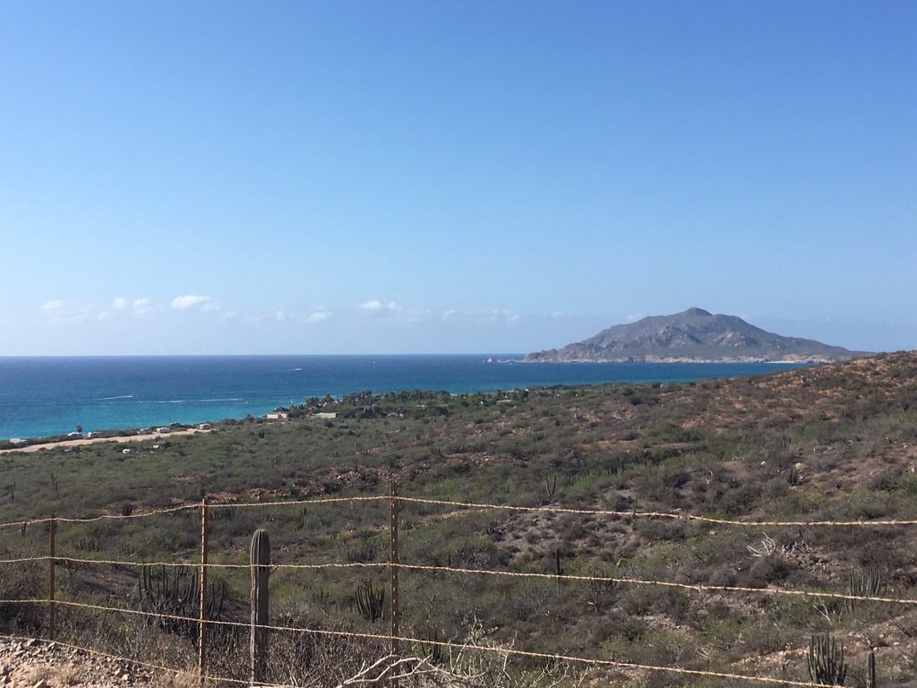 A large mountain looms in the background over blue ocean water on the way into Cabo Pulmo National Park upon arrival from Cabo San Lucas, Mexico photo © Kate Dana