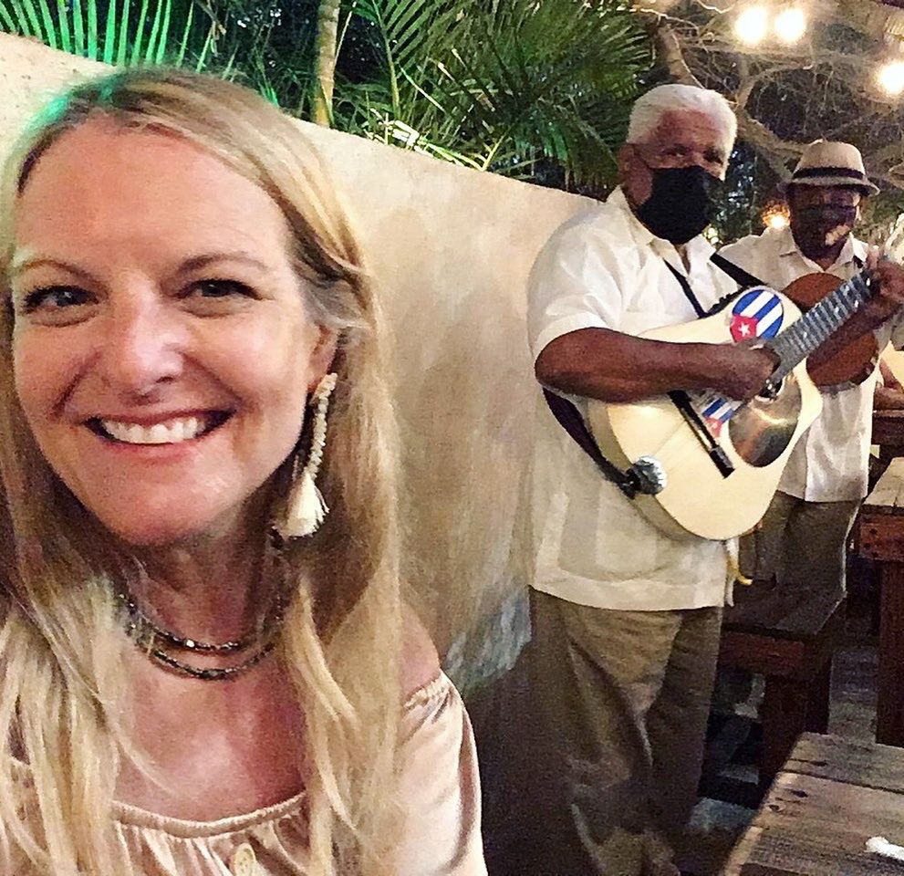 A person enjoys live guitar from two musicians playing at an outdoor restaurant in Cabo San Lucas, Mexico, photo © Kate Dana