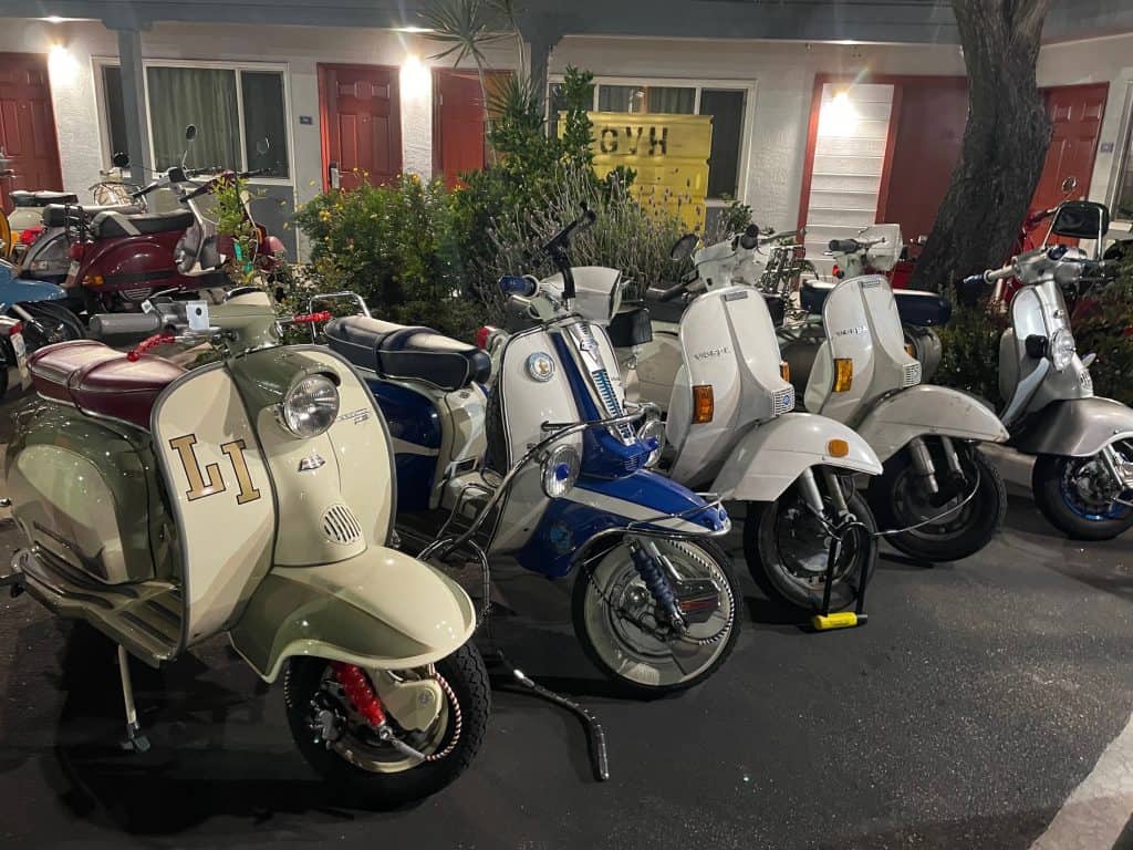 Several vintage Vespas and Lambrettas - manual-shift, Italian motor scooters - gathered for the weekend for the annual Rides of March scooter rally, sit secured with locks and cables for the evening, occupy a small area in the parking lot of the Avenue Inn and Suites in downtown San Luis Obispo, CA, photo ©Kate Dana