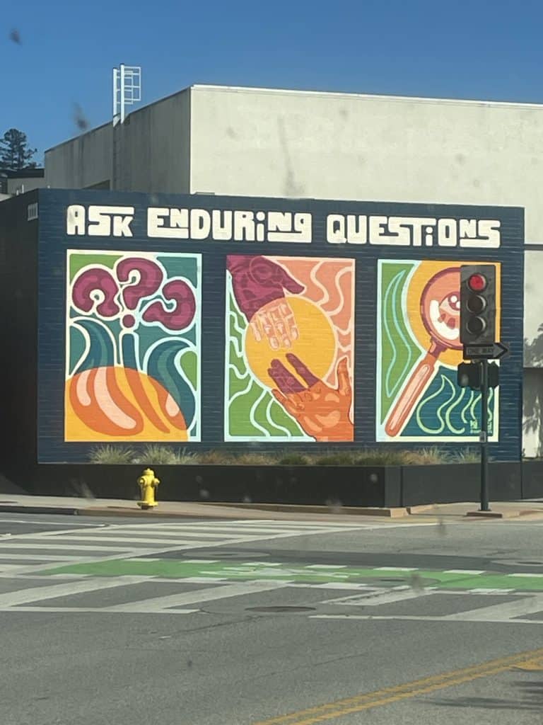 A large, colorful mural with three abstract images in green, burgundy, and orange, announces Ask Enduring Questions in this street mural in San Luis Obispo, near the Santa Maria Valley, California, photo © Kate Dana