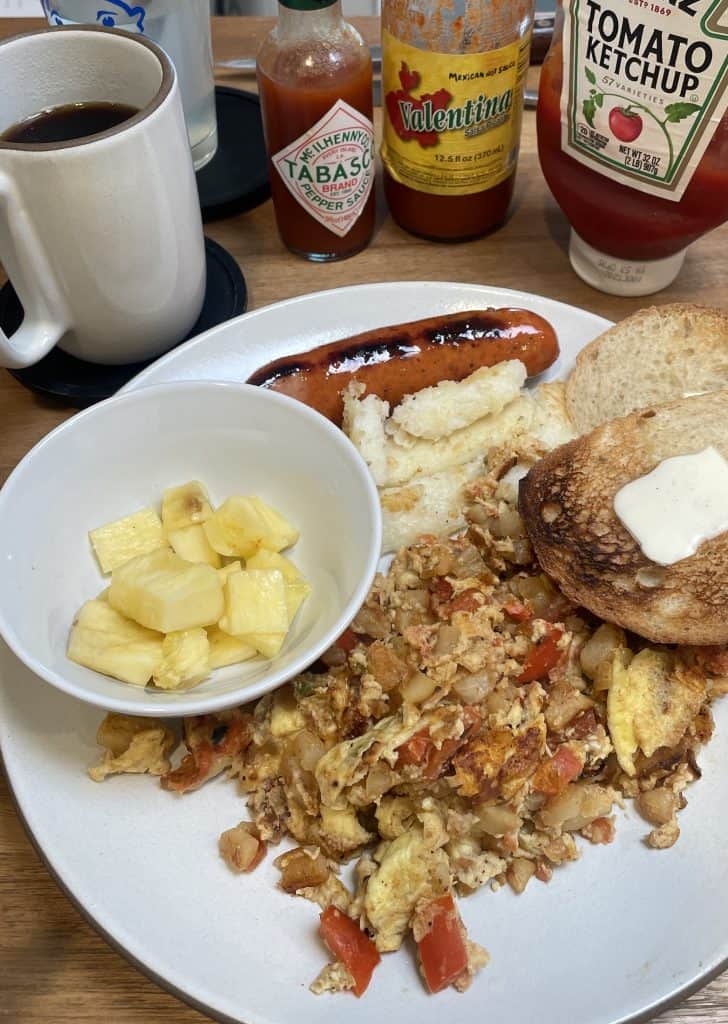 A traditional breakfast of eggs, sausage, toast, and hasbrowns on plate next to a small bowl of pineapple, nourishment as part of the Santa Maria Valley: Best 3-Day Weekend Getaway Guide, Photo © Kate Dana.