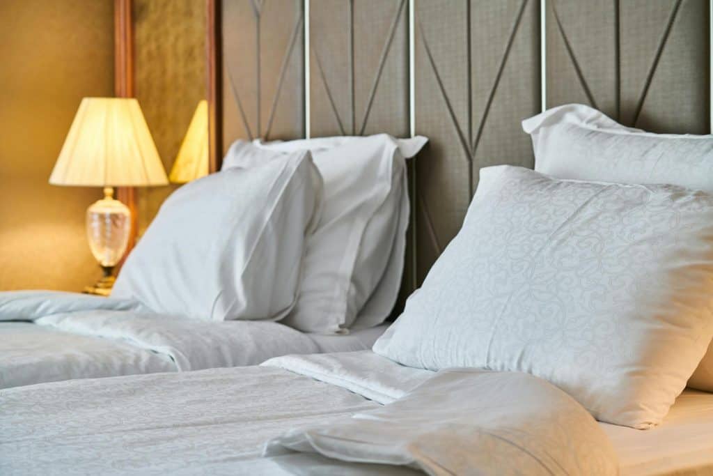 Plump, white pillow grace the fluffy, soft mattress of a queen-sized bed in a lovely hotel in this photo © enginakyurt for pexels