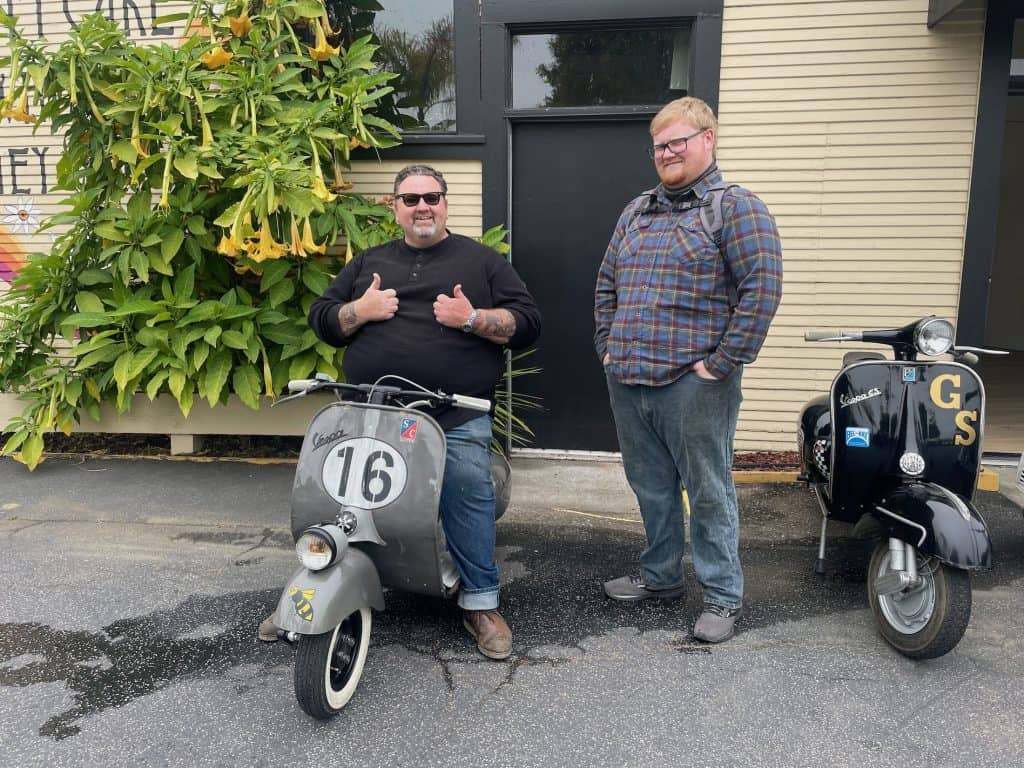 A father and son with their vintage Vespa motor scooters wait in the parking lot of the Crepe Place for the start of the Morning Wood Classic Scooter Weekend ride, photo ©Kate Dana