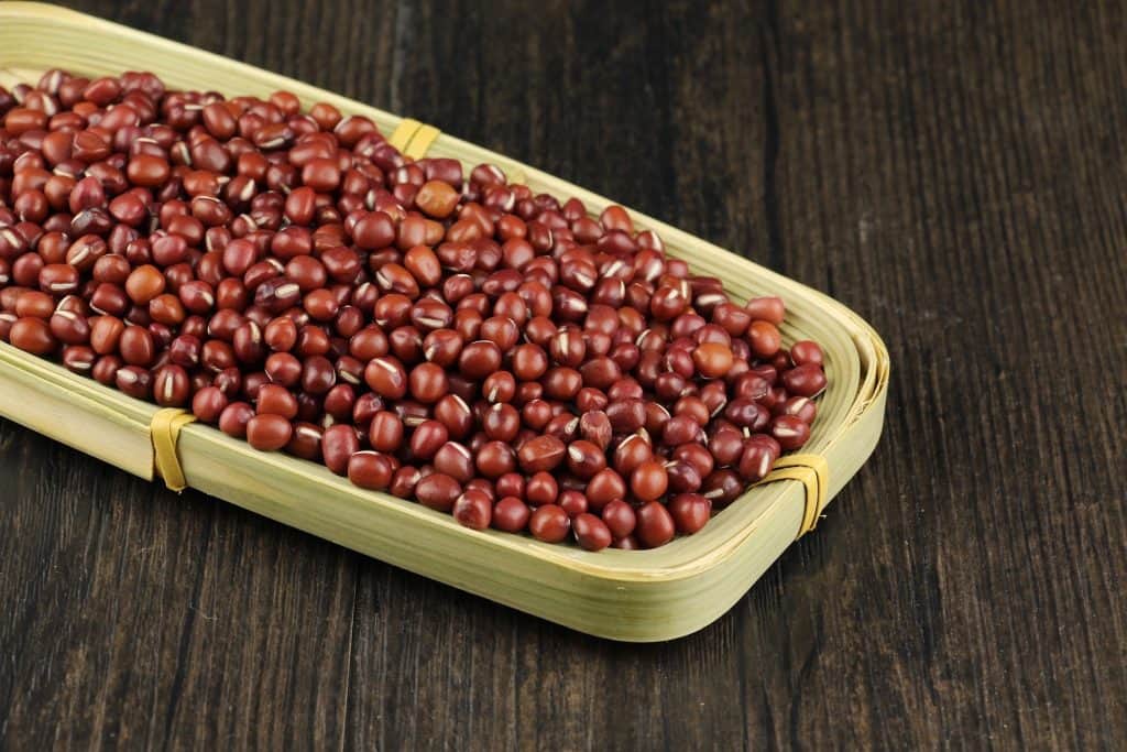Shiny, small, dried red Pinquito beans fill a shallow bamboo tray with their goodness before being cooked to release their smoky, saucy flavor, a must-have meal in the Santa Maria Valley. Photo © bjgaowei2008 for pixabay