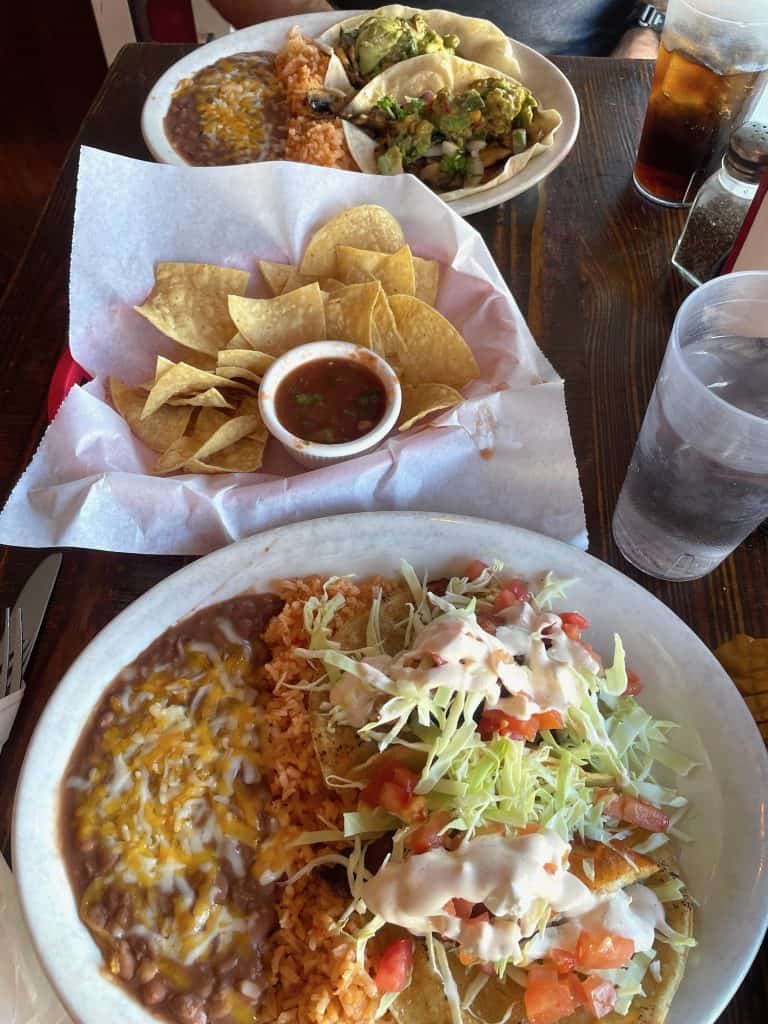 Authentic Mexican food fills a plate with beans, rice, salad, and tacos next to a large basked of chips and salsa on a table at Cocorenos in Long Beach, CA, home of Long Beach Classic Scooter Club's annual Classic Not Plastic Scooter Rally on Memorial Day weekend, photo ©Kate Dana