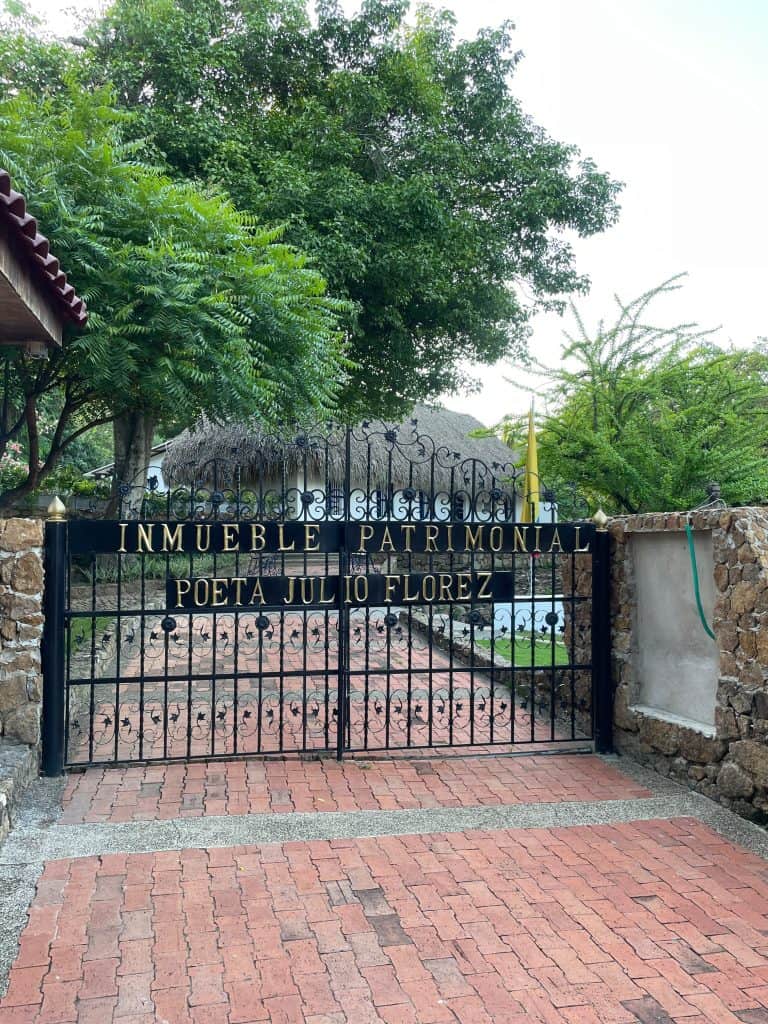 A black iron gate with gold letters announces the driveway to Inmueble Patrimonial Poeta Julio Florez during a day in enchanting Usiacuri, Colombia, photo ©Kate Dana