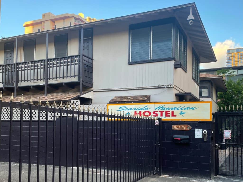 The outside facade of a building marked as a hostel with large windows and a clear blue sky. Hostels worldwide like this one in Honolulu, Hawaii are included in Hostelworld.com's long list of locations and are available when you sign up to join by using their website or app for iOS and Android phones, photo ©Kate Dana