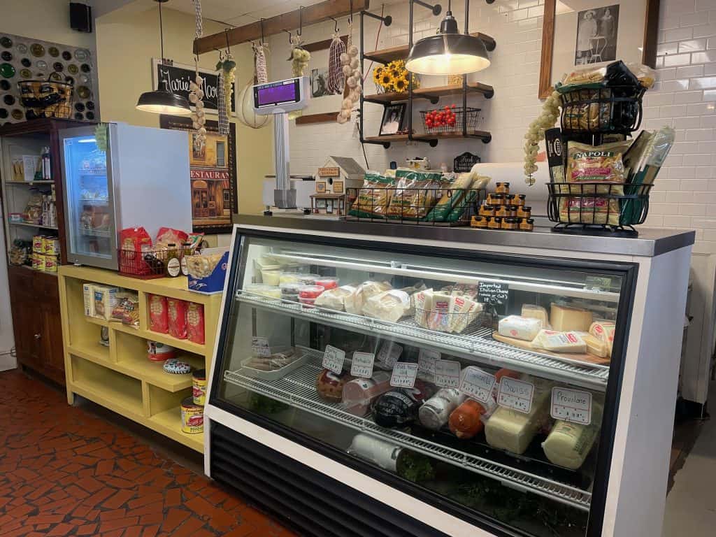 A glass case with meats and cheeses sits next to a shelf with imported Italian pasta and cookies at Marie's Italian Deli in Cumming, GA, photo ©Kate Dana