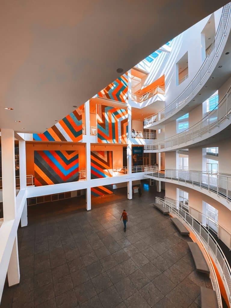 A colorful graphic painted on a far wall beyond the wrap-around atrium with open balconies in a circular shape inside the High Museum of Art in Atlanta, GA, photo ©Ranjith Alingal for Unsplash