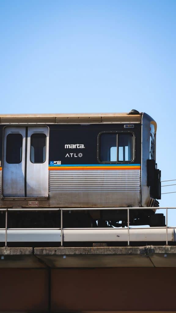 A silver-sided transit car for the MARTA rail system in Atlanta, GA, rides against a blue afternoon sky photo ©Levi Purk for Unsplash