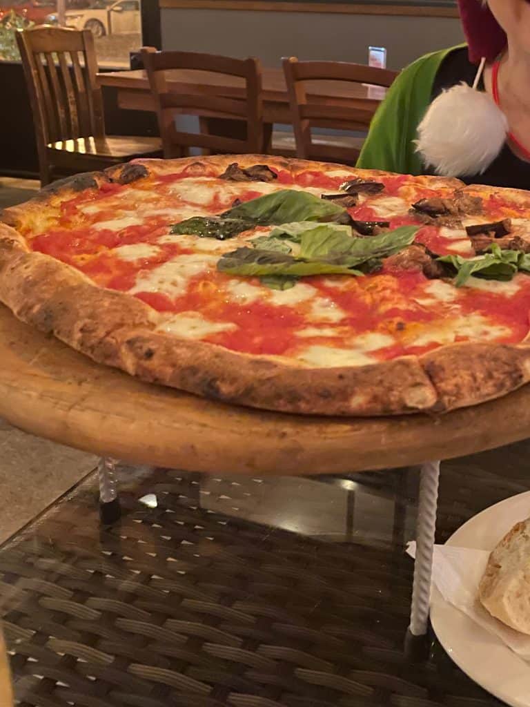 A delicious, perfectly-cooked pizza with fresh basil, mozzarella cheese, and red sauce rests on a table at Sapori de Napoli in Decatur, GA near Atlanta, GA, photo ©Kate Dana