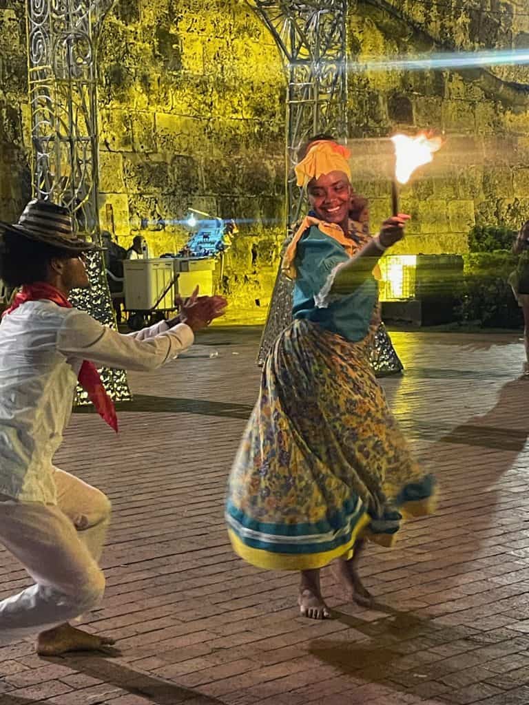 Two dancers in traditional Cumbia dress and bare feet perform with firey torches at night in the plaza near the Torre de Reloj in Cartagena, Colombia, a city similar to  Charleston, S.C., photo ©Kate Dana