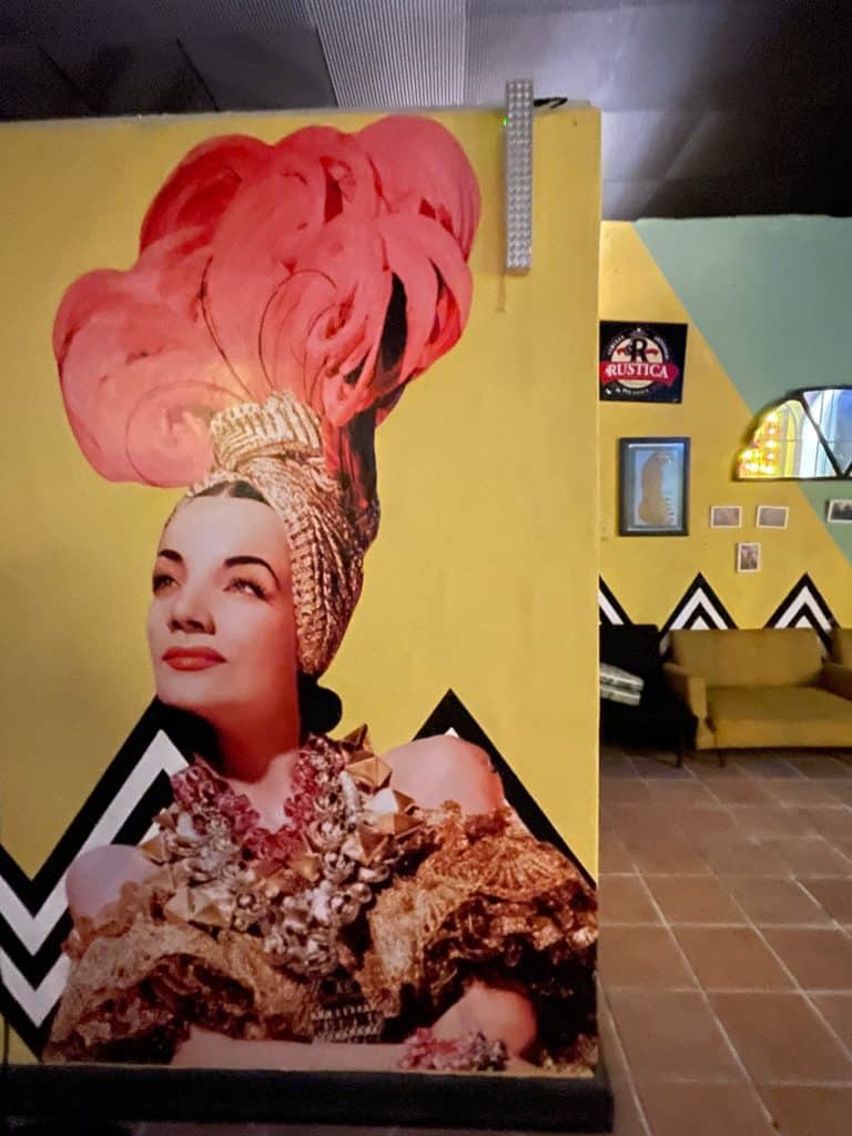 A large, colorful painting on the wall features actress Maria Felix in this mural at La Fundación Mezcalaria in Merida, Mexico, photo ©Kate Dana