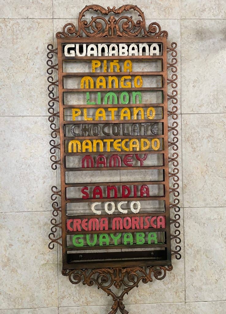 A wooden plaque with colorful letters announces the ice cream flavors available at a café in Merida, Mexico photo ©Kate Dana