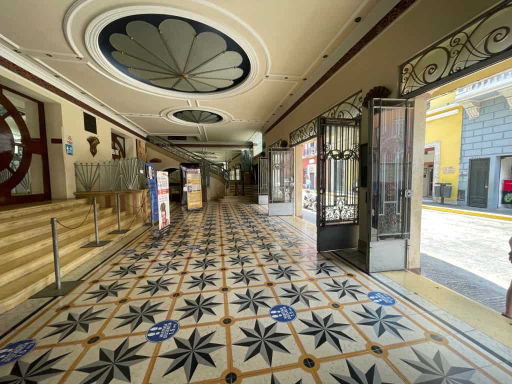 The ornate tiles and glass doors under large round inset lights in the foyer of Teatro Merida in Merida, Mexico, photo ©Kate Dana