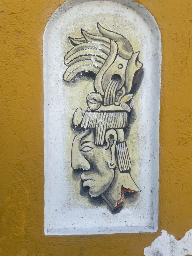 A Yucataneo warrior painting in profile style using gold, black and white paint on a wall in Mexico add to the article Mexican Slang for Beginners: Phrases to Know photo ©Kate Dana