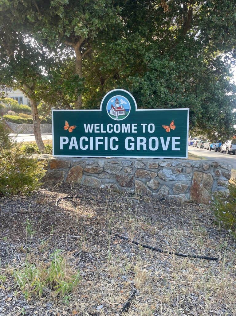 A colorful sign on a grassy field welcomes visitors to Pacific Grove, CA, photo ©Kate Dana