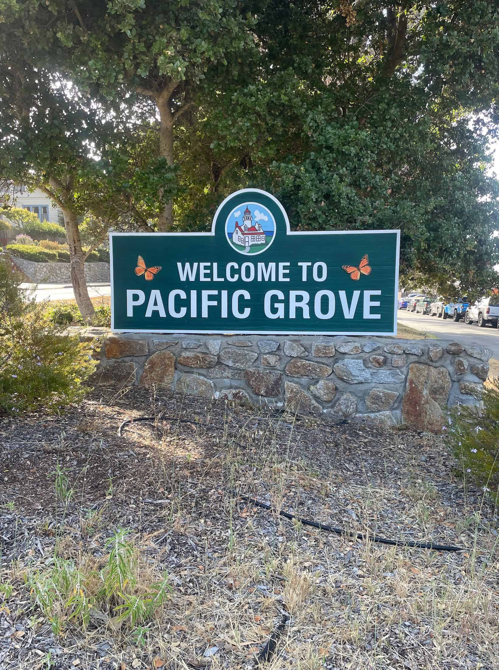 A colorful sign on a grassy field welcomes visitors to Pacific Grove, CA, photo ©Kate Dana