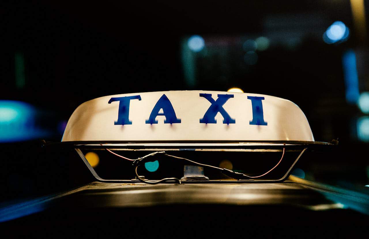 A close-up image of a lighted sign on top of a car announcing TAXI, photo ©neosiam for pexels.com
