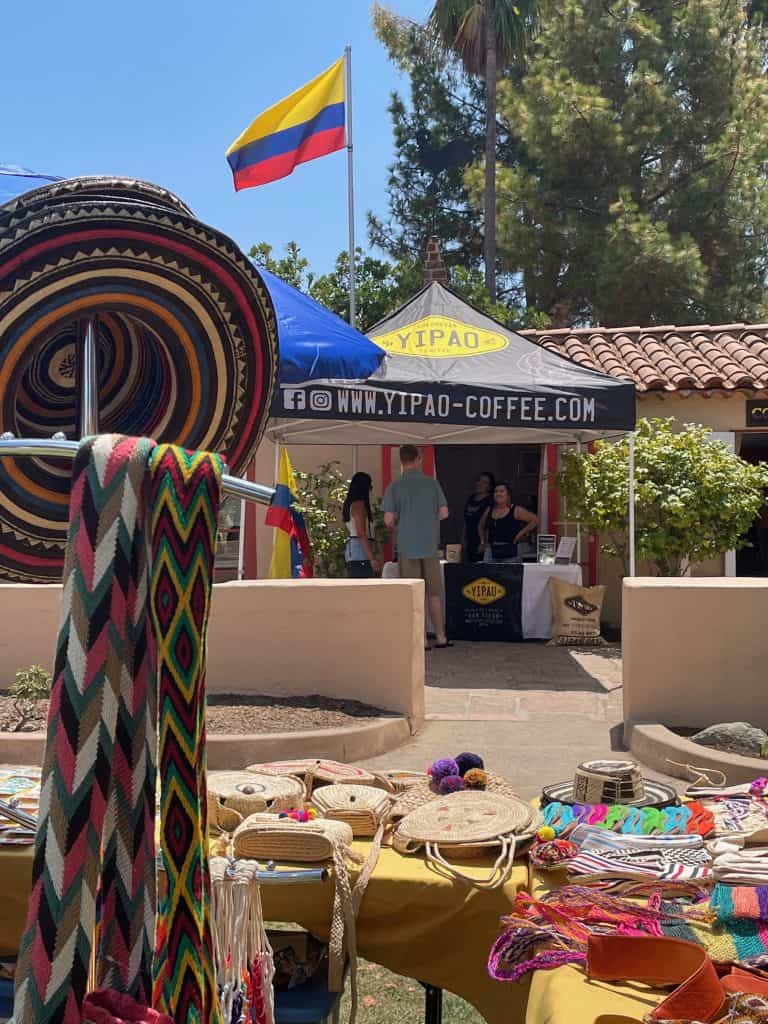 Vendor tables sell mochilas and recuerdos outdoors at Casa de Colombia in Balboa Park, San Diego, photo ©Kate Dana