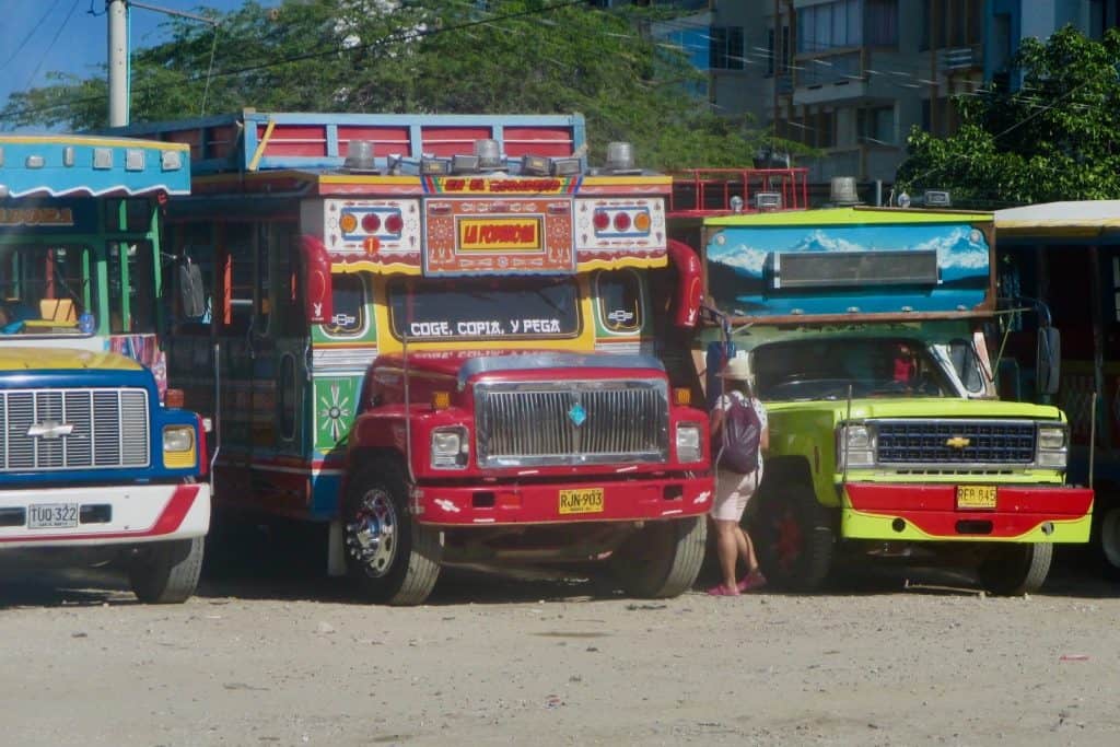Colorful chiva buses line up side by side outdoors in Colombia, photo ©Kate Dana