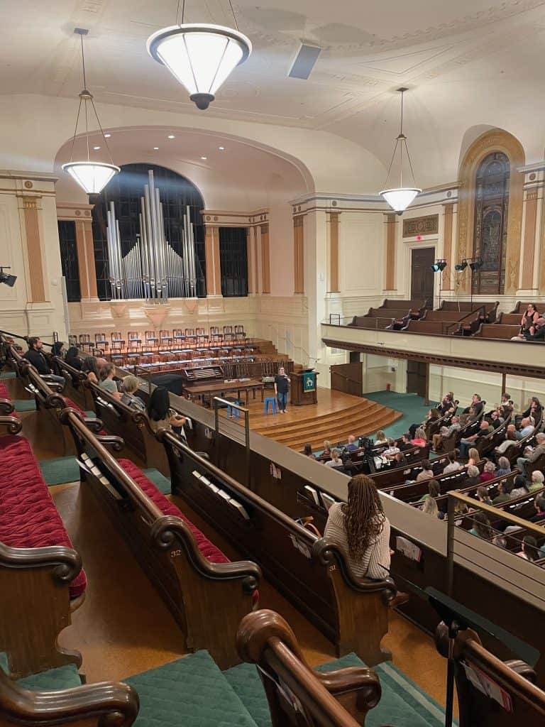 A view of the sanctuary of Calvary Presbyterian Church in San Francisco, CA taken from the balcony shows a large silver pipe organ, chairs, and stained glass, photo ©Kate Dana