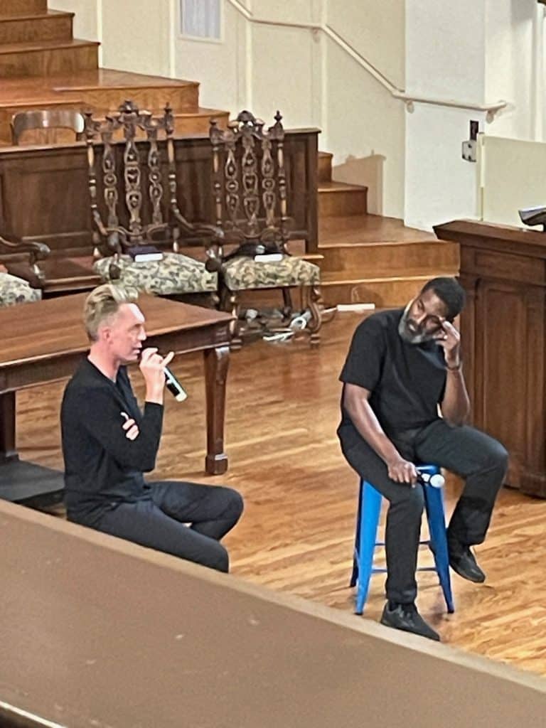 Joshua Fields Millburn and T.K. Coleman, two members of The Minimalists, sit on stools and talk on a stage, photo ©Kate Dana