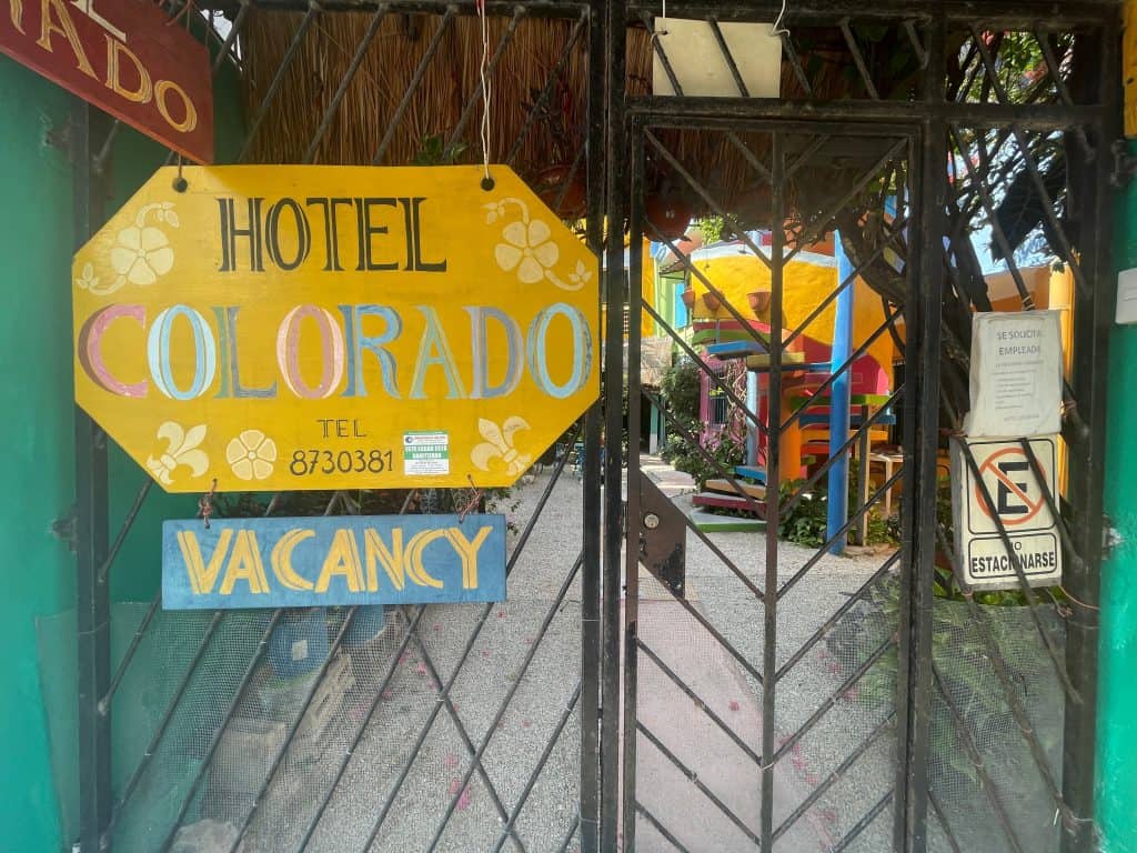 A yellow sign announces the Hotel Colorado on a fence outside the establishment, photo ©Kate Dana