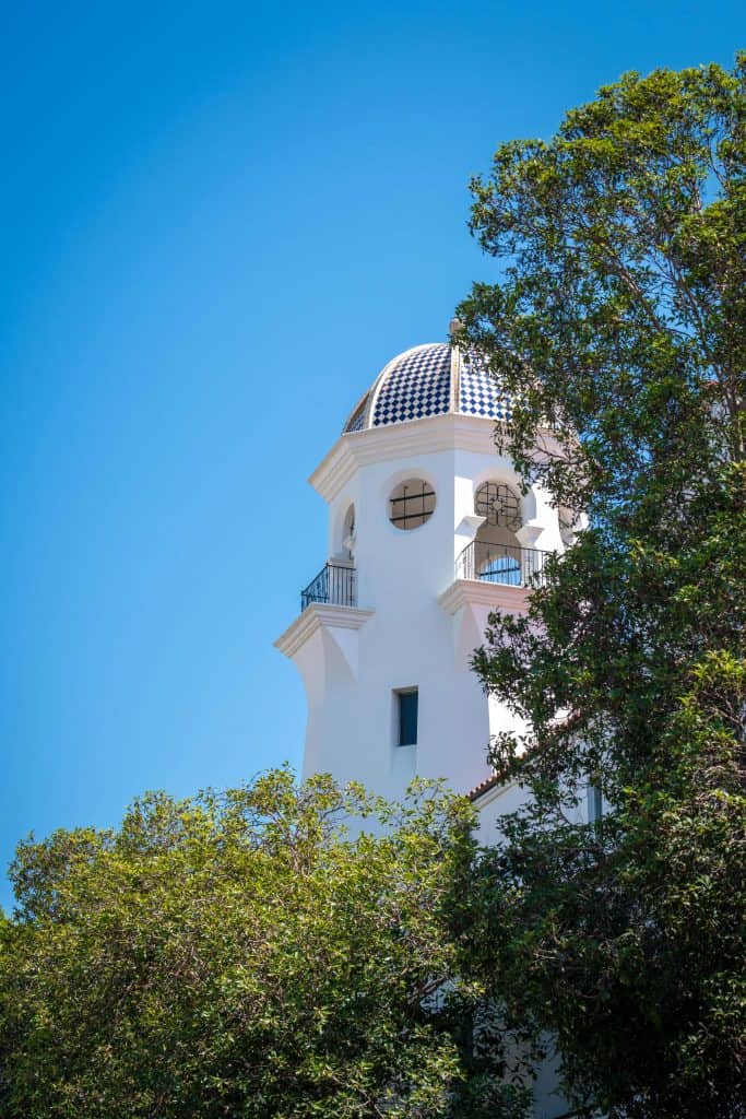 An historic tower showing Spanish architecture influences rises in the sky over Santa Barbara, CA, photo @haha for Pexels