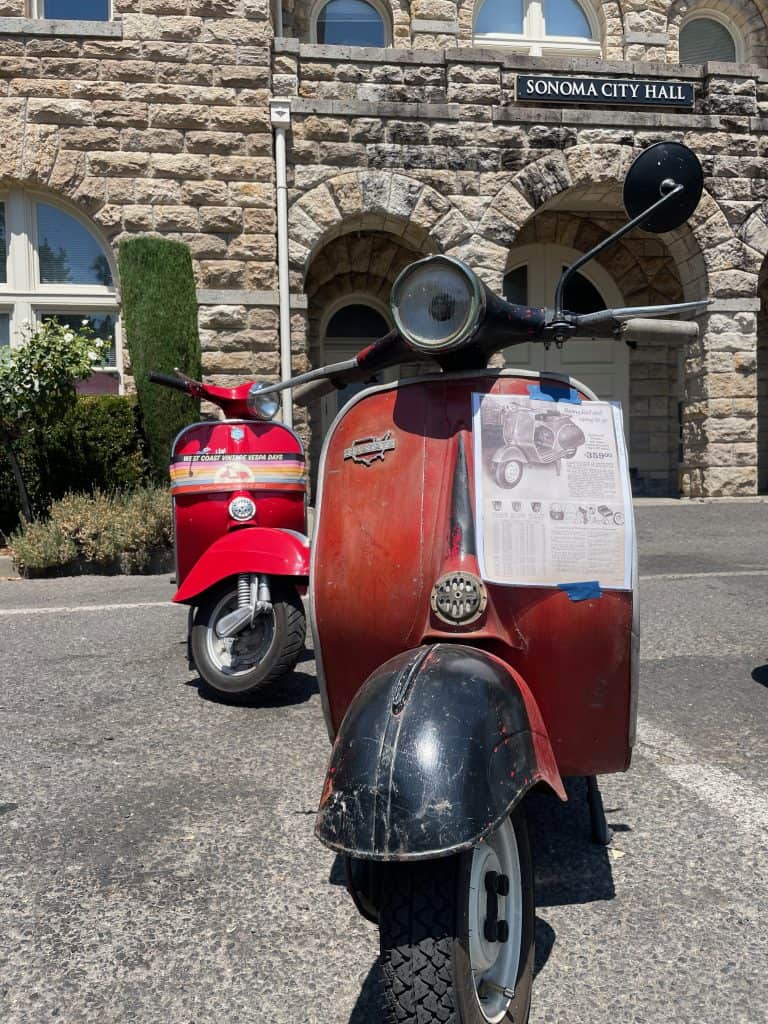 Vintage scooters line up in front of the Sonoma City Hall in Sonoma, CA during West Coast Vintage Vespa Days 2023, photo ©Kate Dana