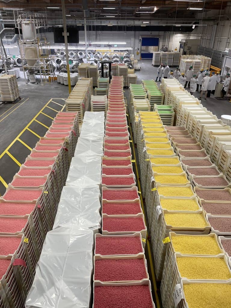 Large colorful palettes of Jelly Belly candies in pink, white, red yellow, and tan, stacked up several feet high, line the floors of the Jelly Belly Factory in Fairfield, CA, photo ©Kate Dana