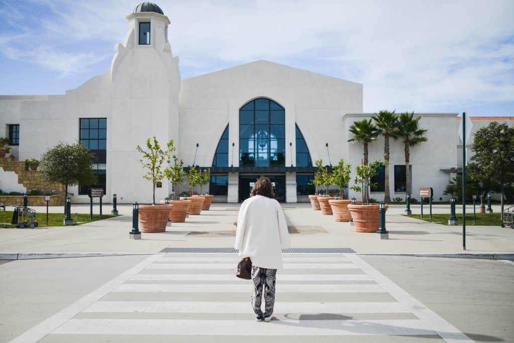 A person walking towards the white facade of the Santa Barbara airport on a sunny day in this photo © Stocksnap for Pixabay