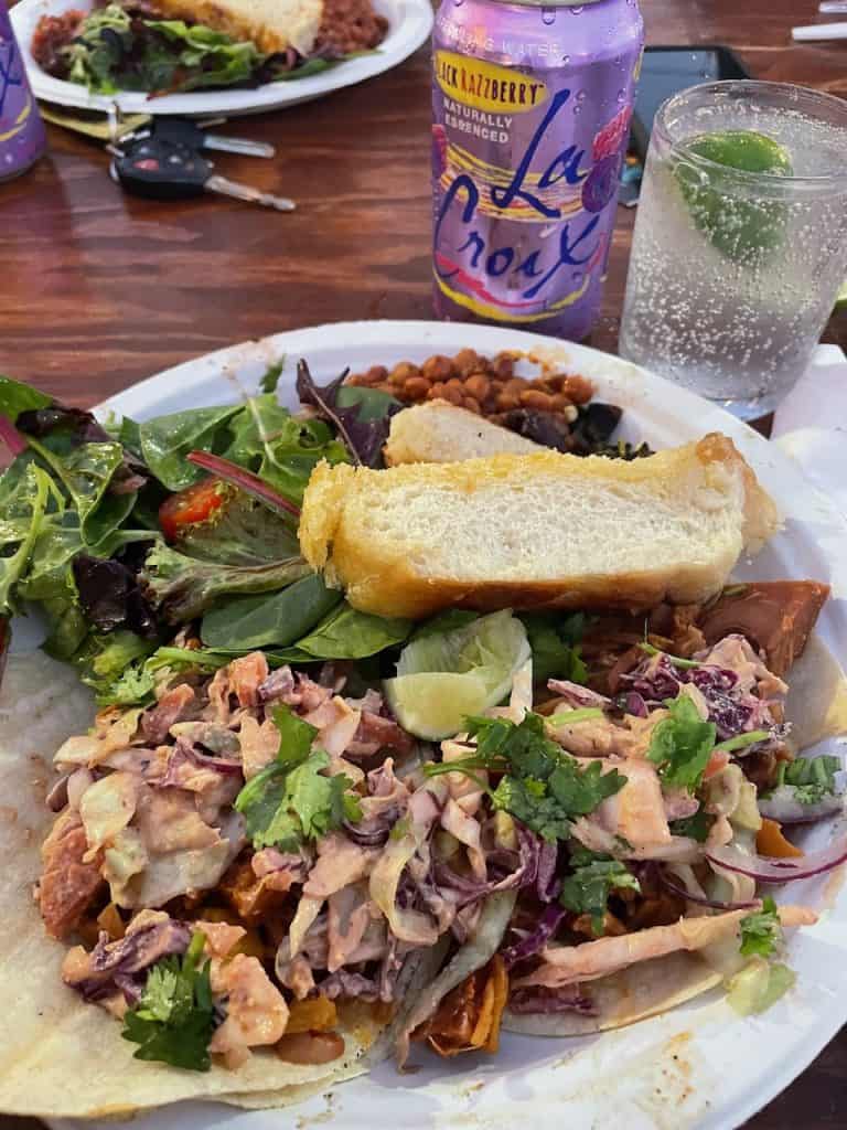 Shrimp and vegetarian tacos on a plate with toasted bread, salad, and pink beans next to a can of La Croix sparking water, photo ©Kate Dana