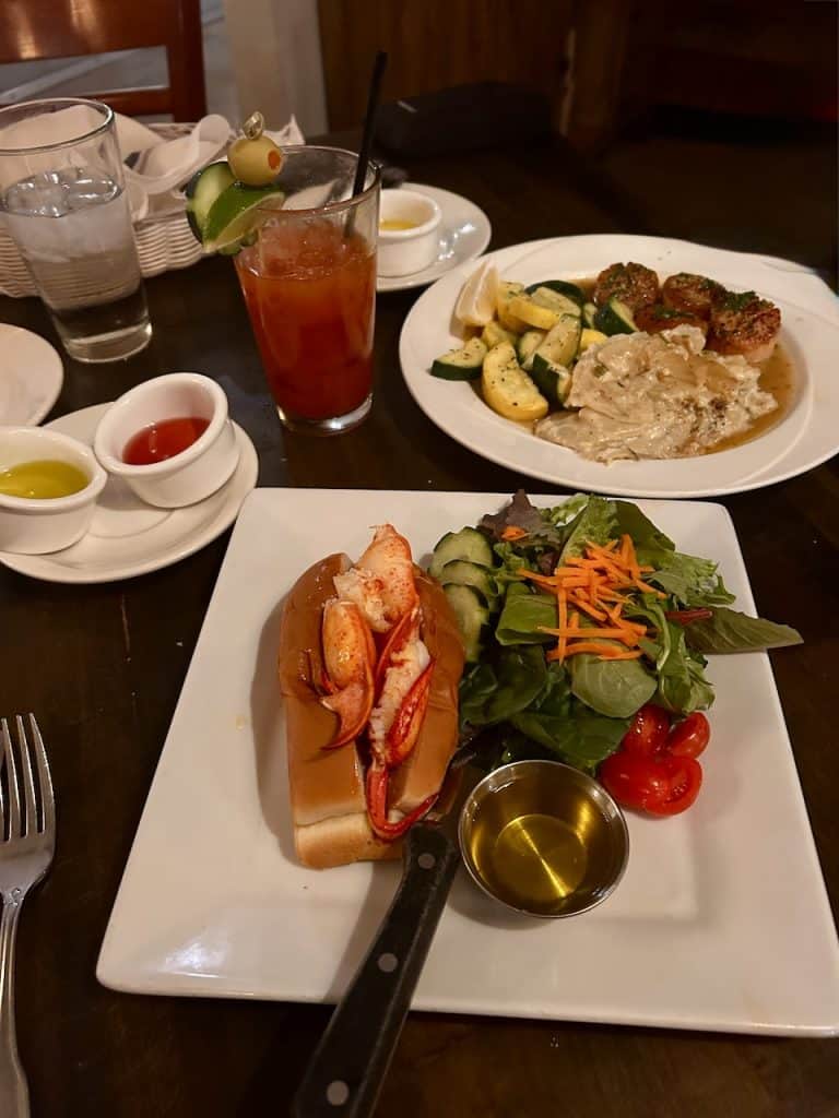 A lobster roll and pasta with frutas del mar on a table at Ada's Fish House in Pismo Beach, California