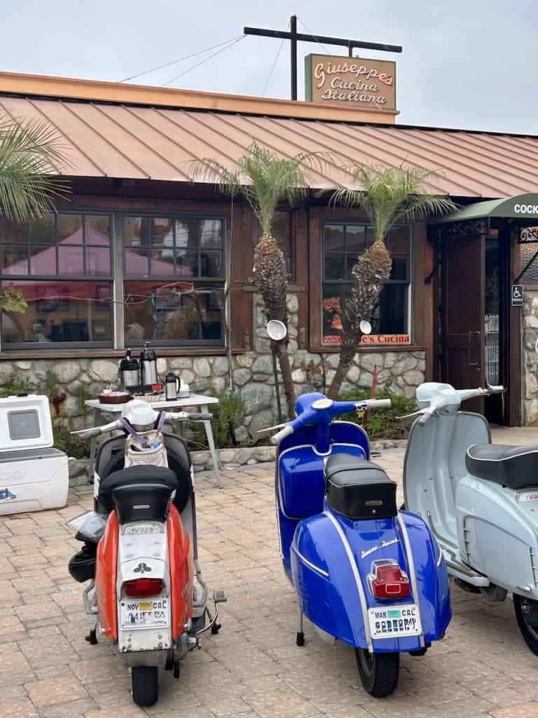 Three vintage Vespas, Italian motorscooters, parked outside Giuseppe's restaurant in Pismo Beach, California