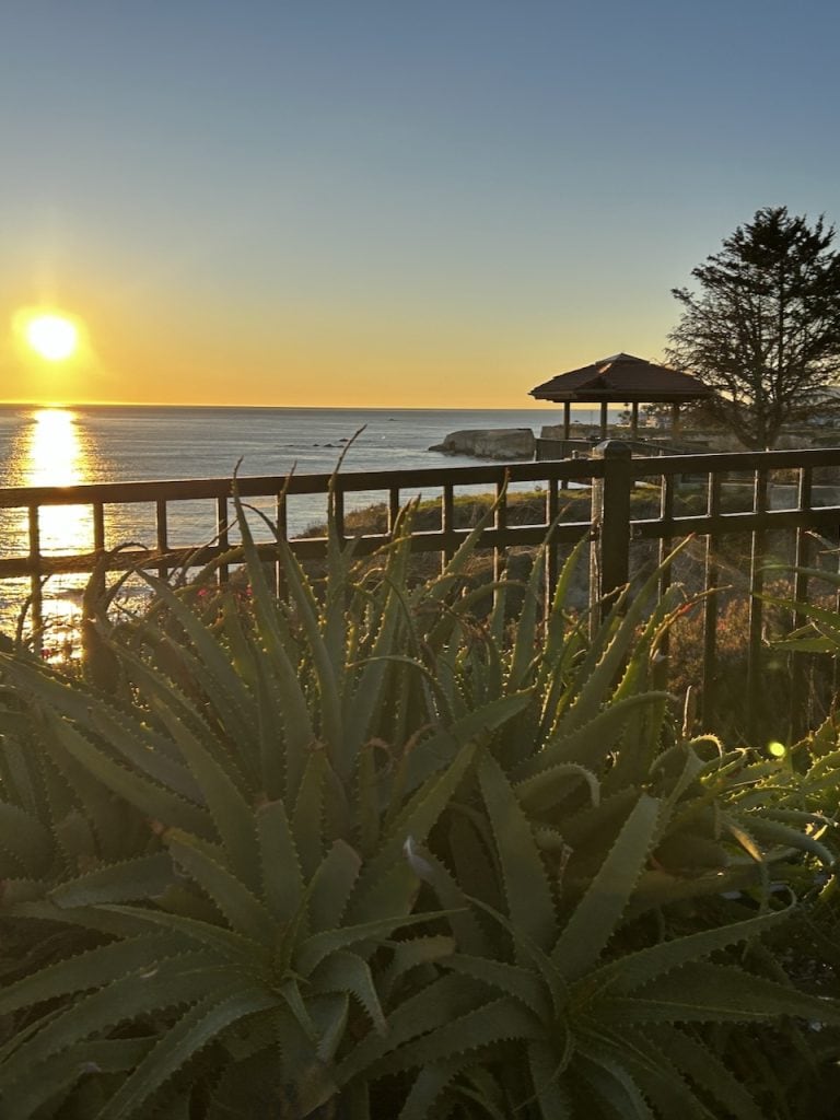 A yellow sun sets over the ocean by Inn at the Cove near Pismo Beach, California