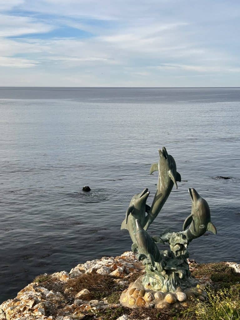 A statue of jumping dolphins in front of an ocean view at Inn at the Cove, near Pismo Beach, California
