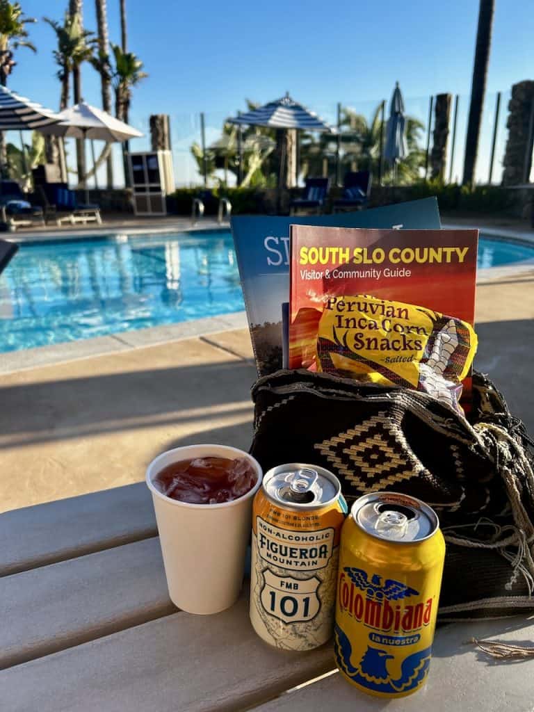 A bag with snacks and several drinks on a poolside table at Inn at the Cove near Pismo Beach, CA