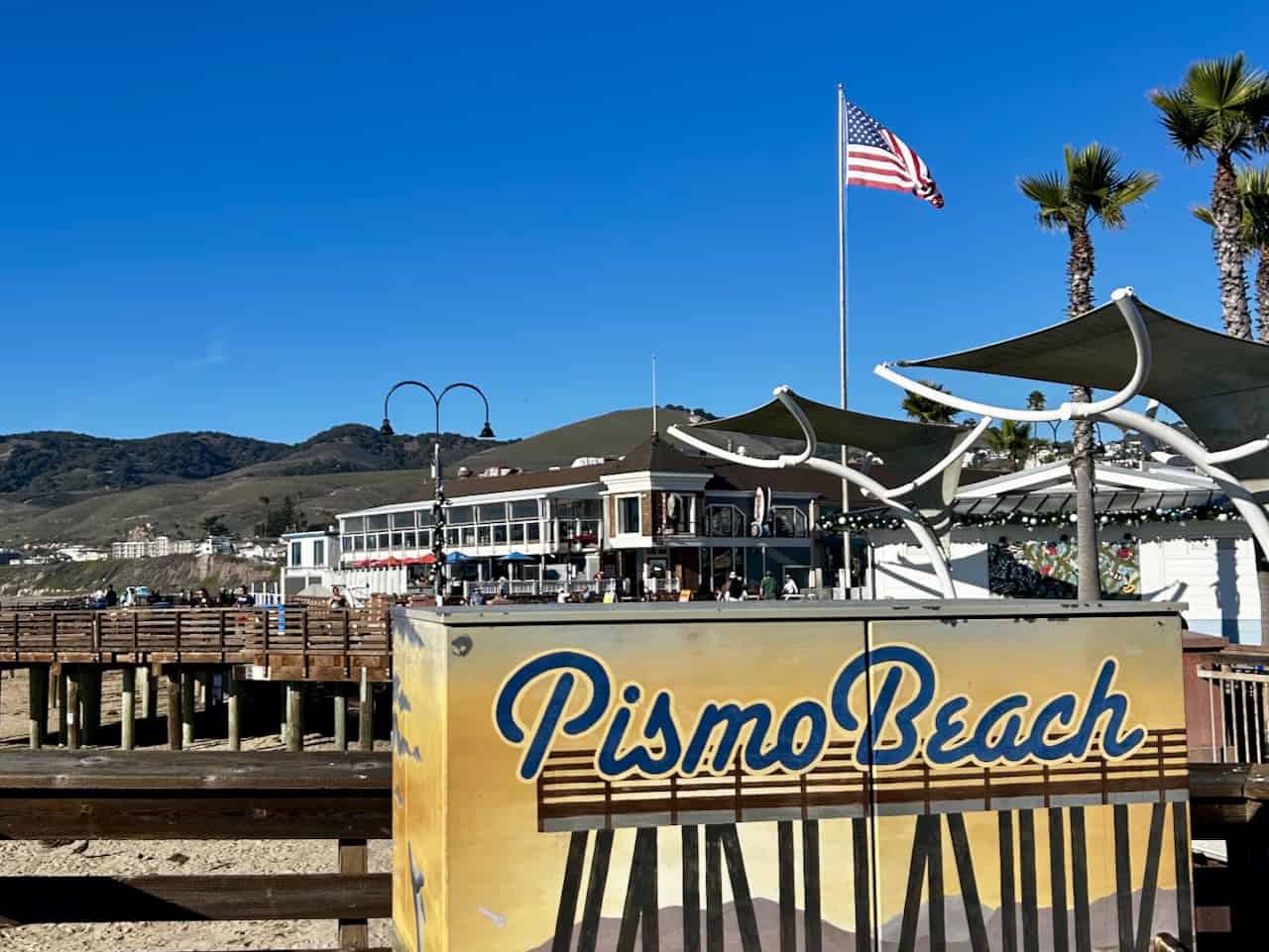 A colorful, electrical box painted with the words Pismo Beach against a bright, blue sky