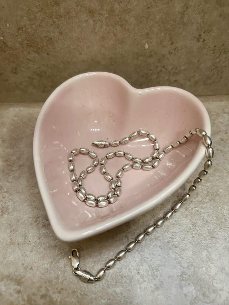 A pink, heart-shaped trinket tray holds a shimmering string of Charleston Rice Beads, photo ©Kate Dana