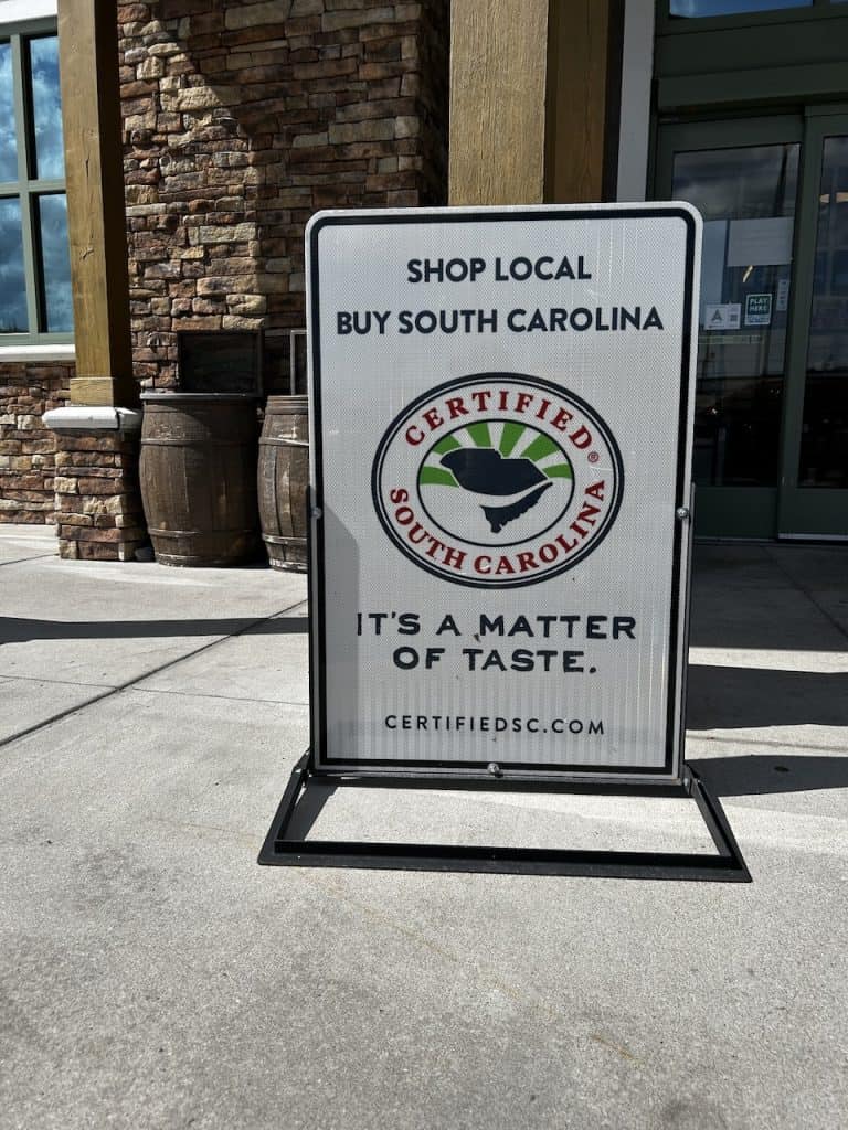 A sign on a sidewalk outside a store tells customers, "Shop Local," near Charleston, S.C., photo ©Kate Dana