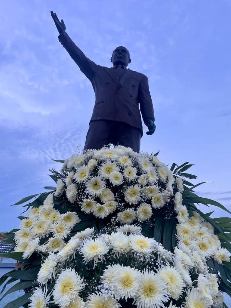 A Statue of Rafael Meglar and bunches of white daisies in the central plaza on Isla Cozumel, Mexico ©Kate Dana
