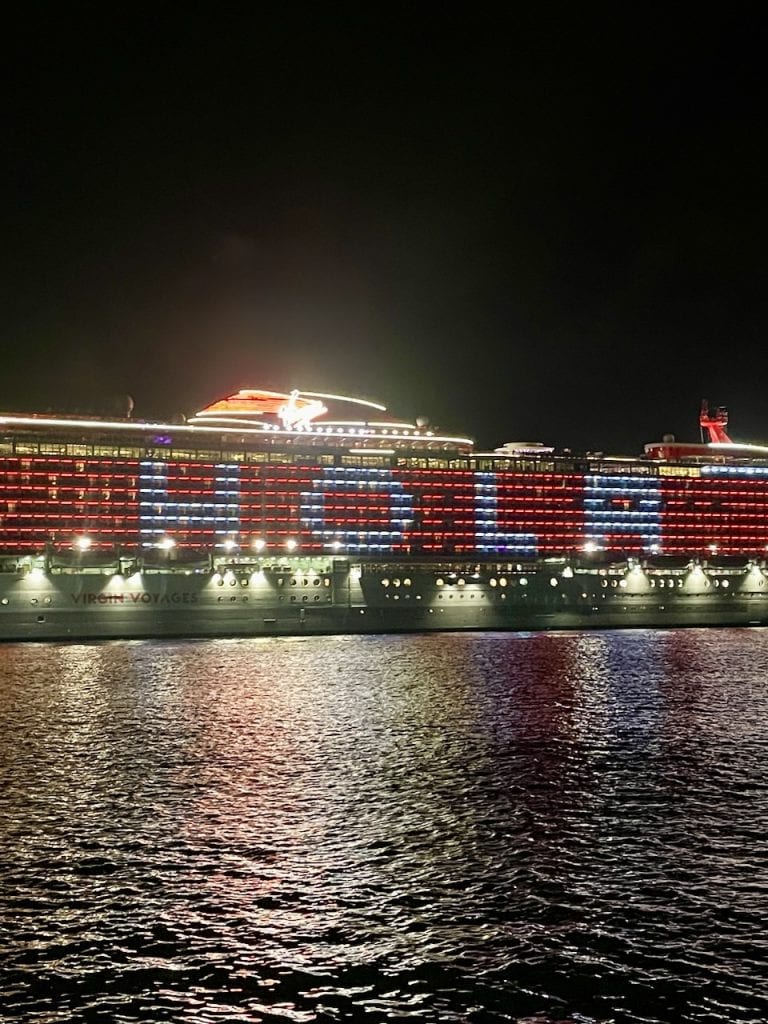 A huge cruise ship with the windows lit up spells "HOLA" docked near Isla Cozumel, Mexico, photo ©Kate Dana