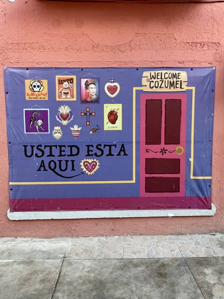 A colorful storefront painting declares "Usted esta aqui," you are here, in Cozumel, Mexico, photo ©Kate Dana