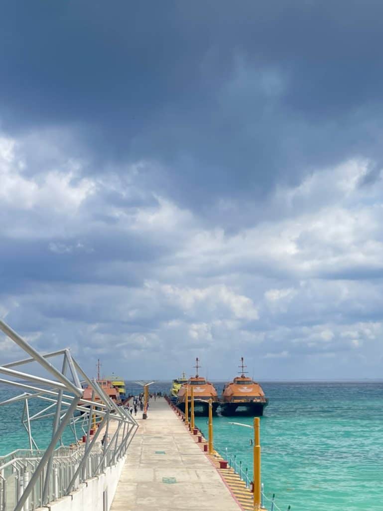 Two brightly-colored ferry boats at the end of a long dock over bright blue water near Isla Cozumel, Mexico, photo ©Kate Dana