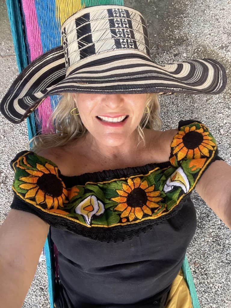 a person in a colorful sun hat and blouse relaxes in a hammock on Cozumel Island, Mexico photo ©Kate Dana