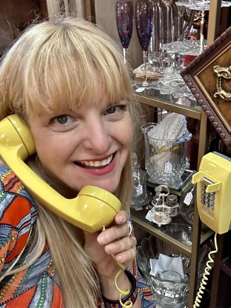 Cocameca founder Kate Dana holds a vintage yellow phone receiver in an antique store, photo ©Kate Dana