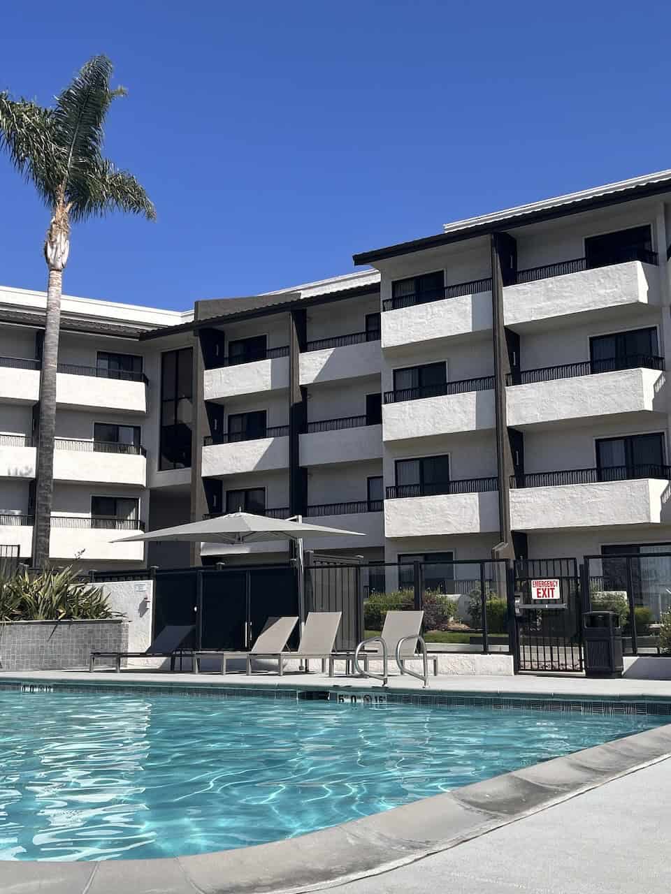 The exterior of a hotel with a blue swimming pool and palm trees ©Kate Dana