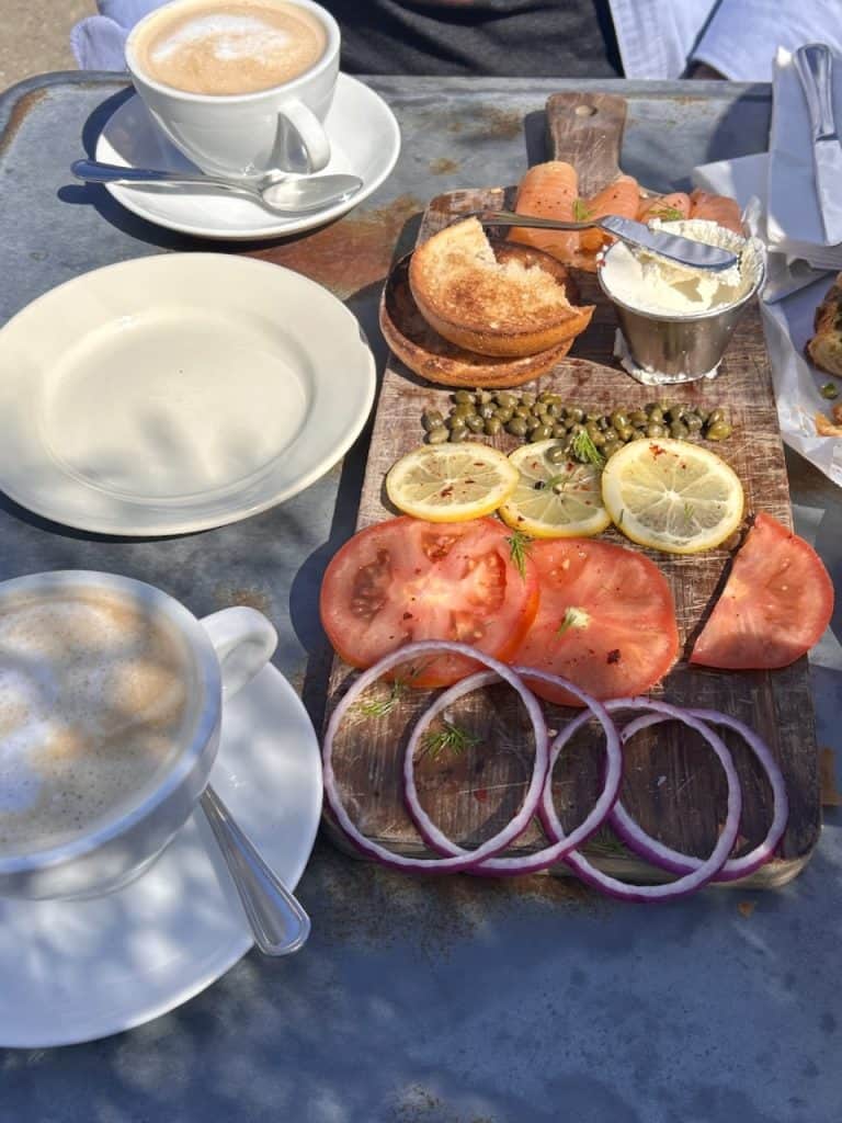 A rustic tabletop with an impressive spread of bagels, lox, and cream cheese, photo © Kate Dana