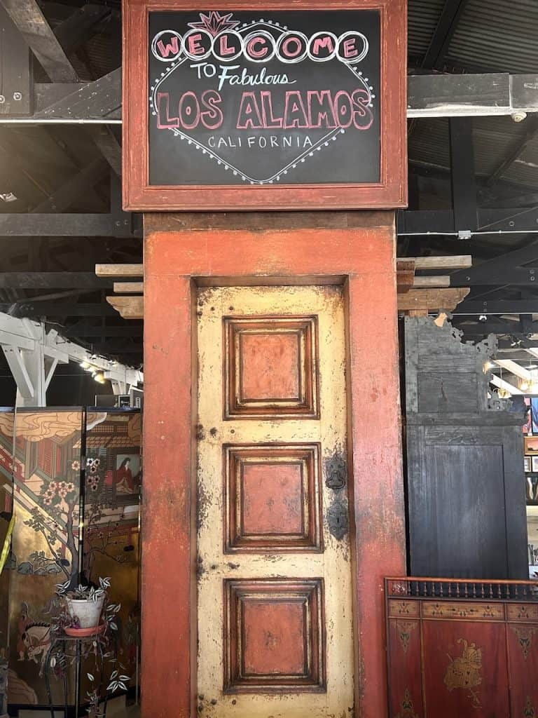 A hand painted sign and rustic door announce "Welcome to Fabulous Los Alamos", photo ©Kate Dana